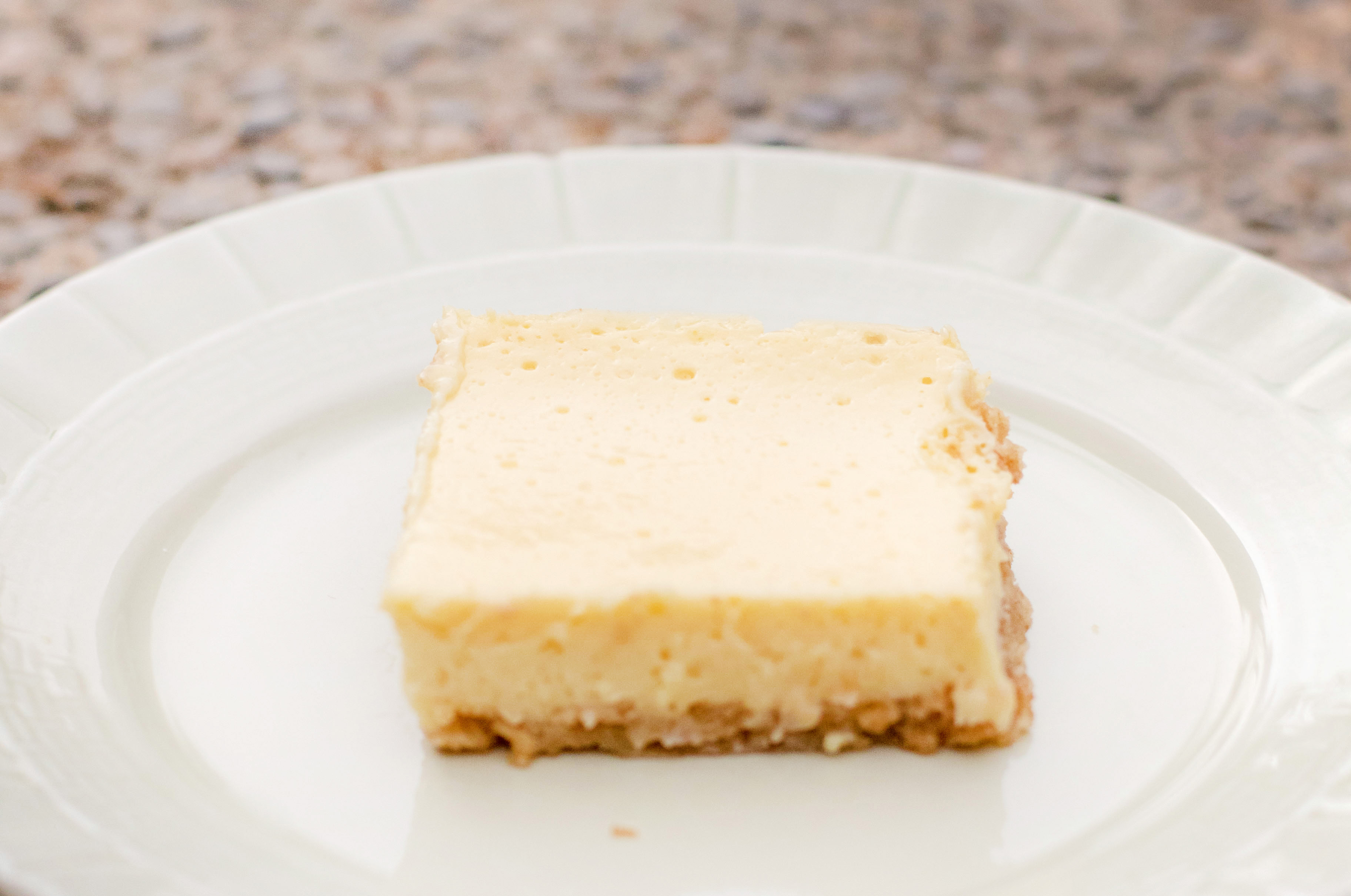 Sour cream lemon bar on a green plate outside in the backyard
